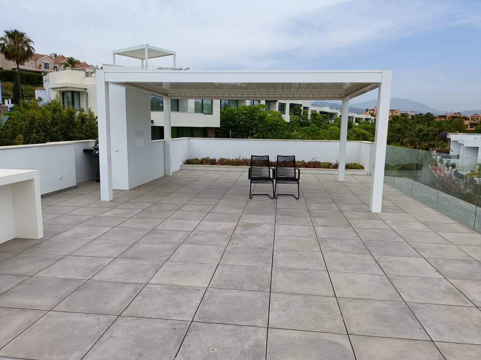 Roof terrace with a finished bioclimatic pergola by Solteana, paving laid and views over the valley